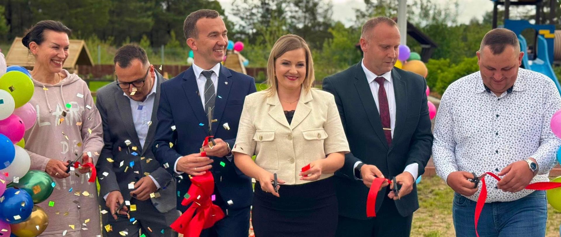 kilkanaście osób stoi i przecina wstęgę 