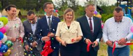 kilkanaście osób stoi i przecina wstęgę 