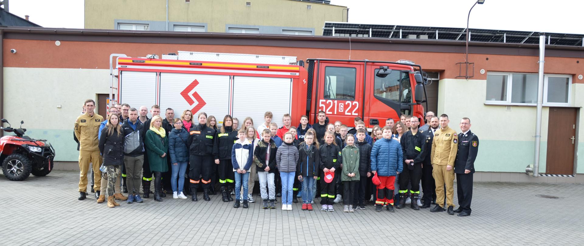 Zdjęcie pamiątkowe uczestników i opiekunów na tle samochodu pożarniczego