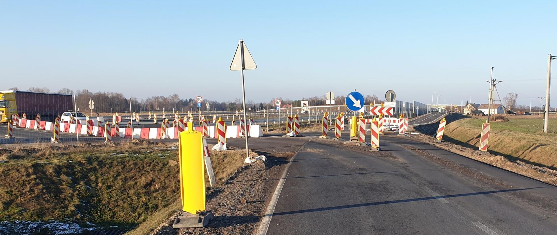 Miejsce włączenia drogi zbiorczej do ciągu głównego S7 oznakowane biało-czerwonymi słupkami i znakami drogowymi.