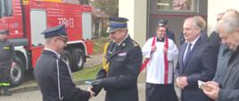 Pomorski komendant wojewódzki Państwowej Straży Pożarnej wręcza kluczyki druhowi, obok zaproszeni goście.
