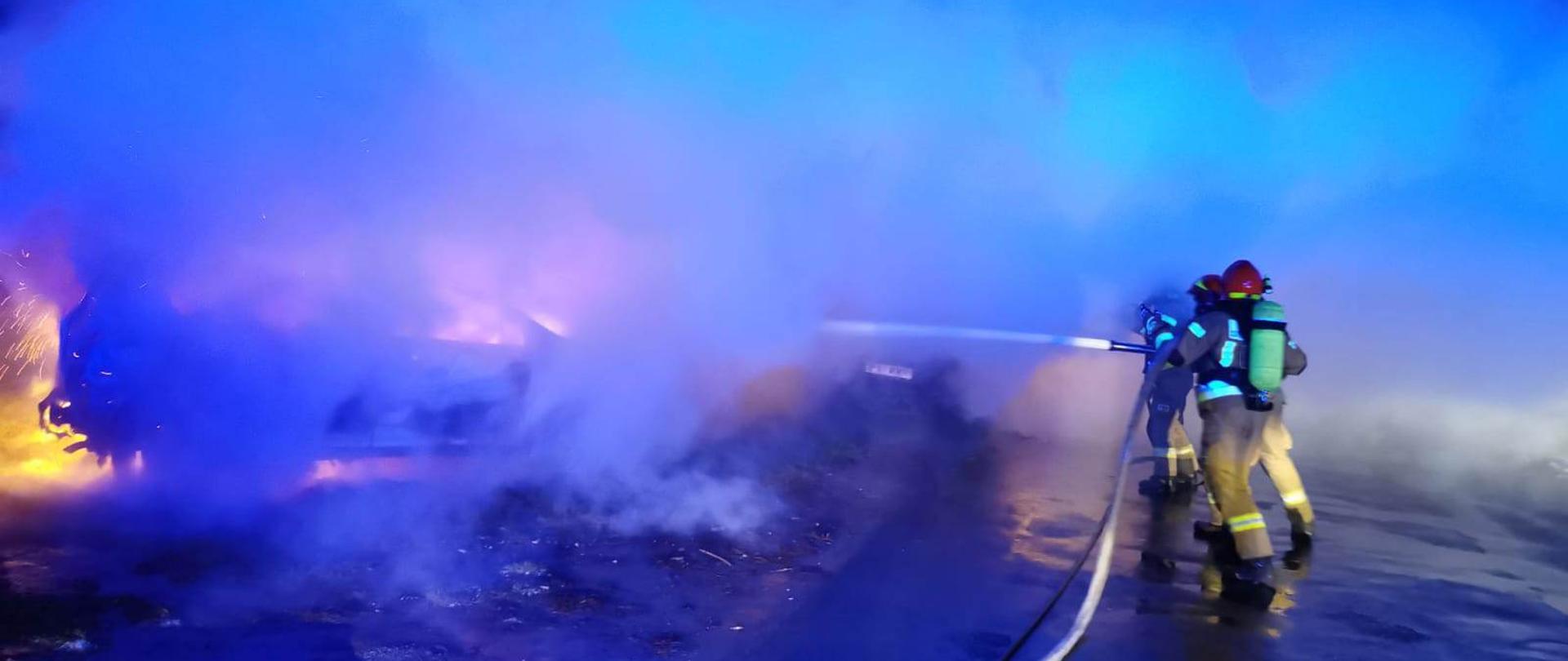 Pora nocna. Duże zadymienie. Widać funkcjonariuszy. Palą się dwa auta.