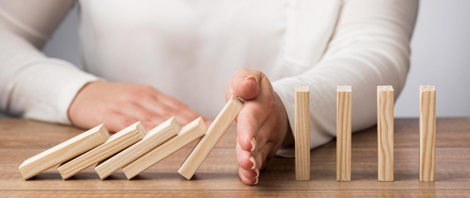 Dłoń powstrzymująca łańcuch domino