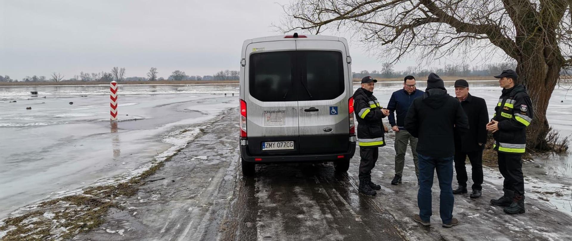 Na zdjęciu dwaj funkcjonariusze Państwowej Straży Pożarnej oraz przedstawiciele Gminy Boleszkowice. Mężczyźni stoją u brzegów rzeki Odry i rozmawiają.