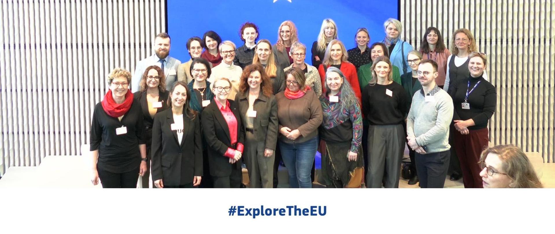 Grupa ludzi stoi na tle flagi Unii Europejskiej 