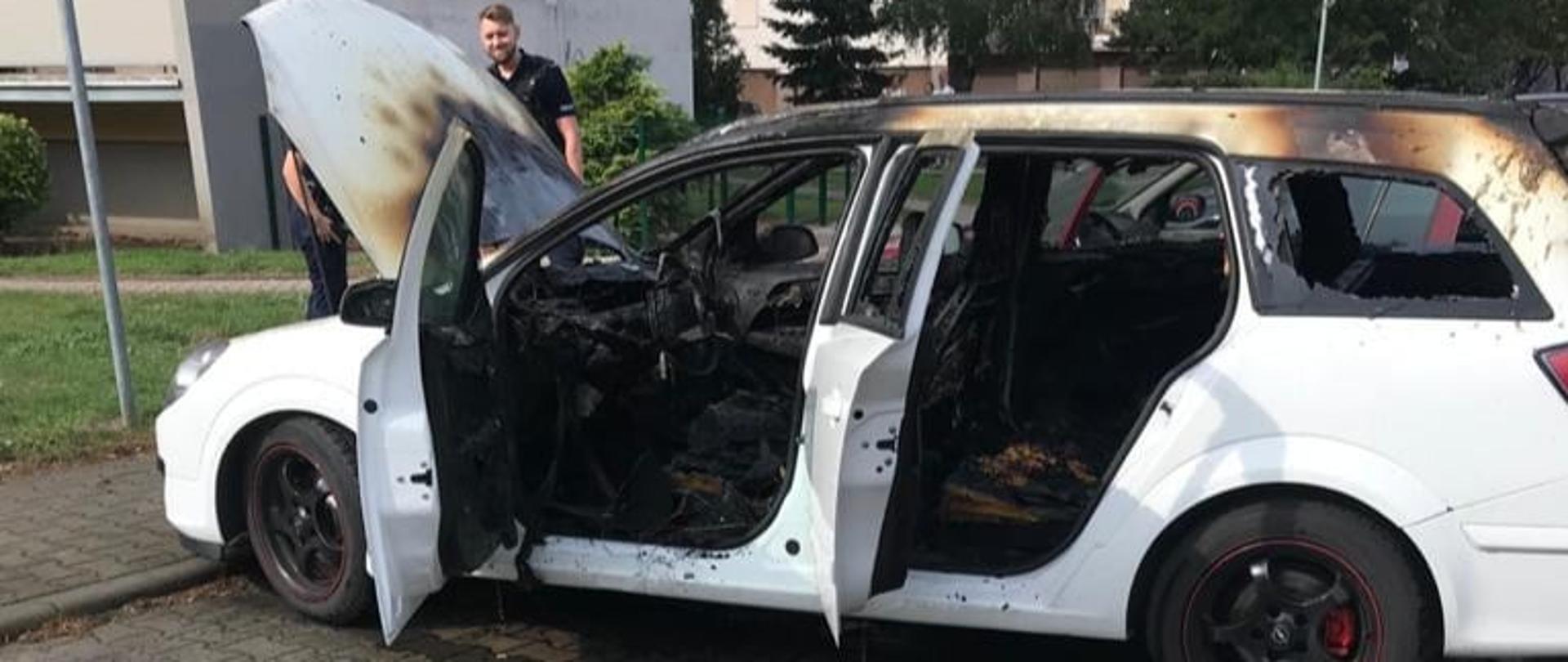 Zdjęcie przedstawia wrak spalonego samochodu osobowego marki Opel astra na tle bloków przy ul. Droga Leśna w Obornikach. 