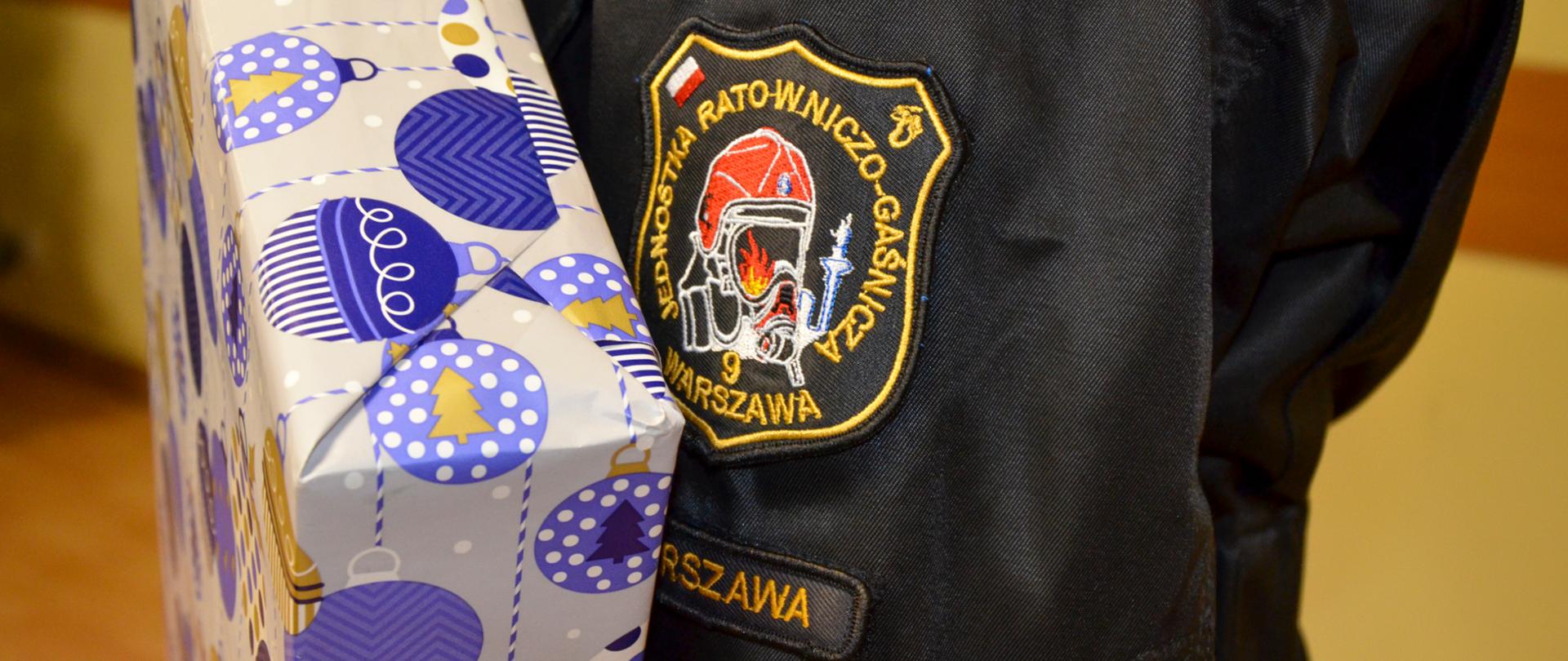 Strażak trzyma ozdobnie zapakowany laptop.