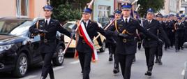 Zdjęcie przedstawia strażaków oraz gości podczas przemarszu ulicą 3 Maja w Koninie podczas obchodów Dnia Strażaka