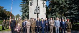 Uczestnicy uroczystości stoją pod pomnikiem