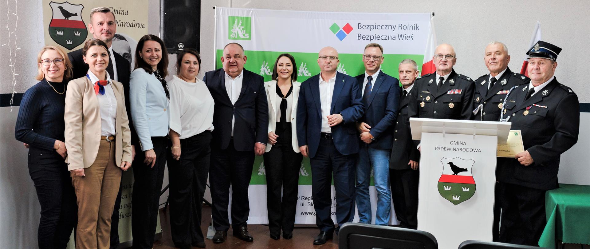 Osoby pozują do zdjęcia na tle roll-upów KRUS oraz Gminy Padew Narodowa