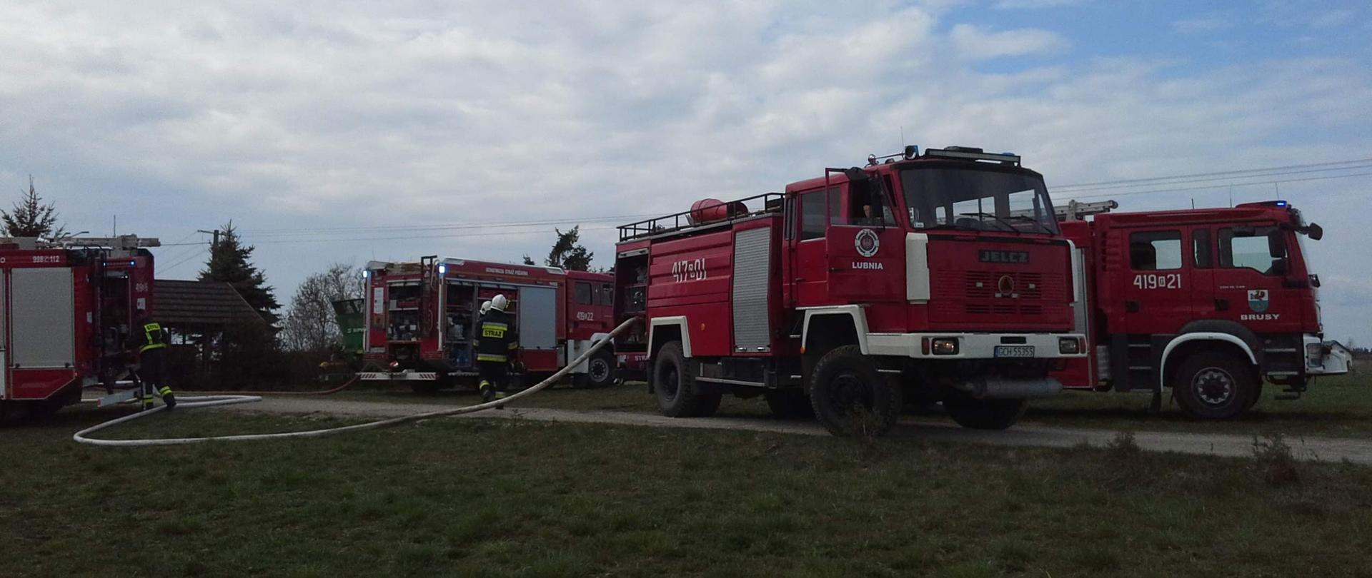 Wozy strażackie z rozwiniętymi liniami gaśniczymi.