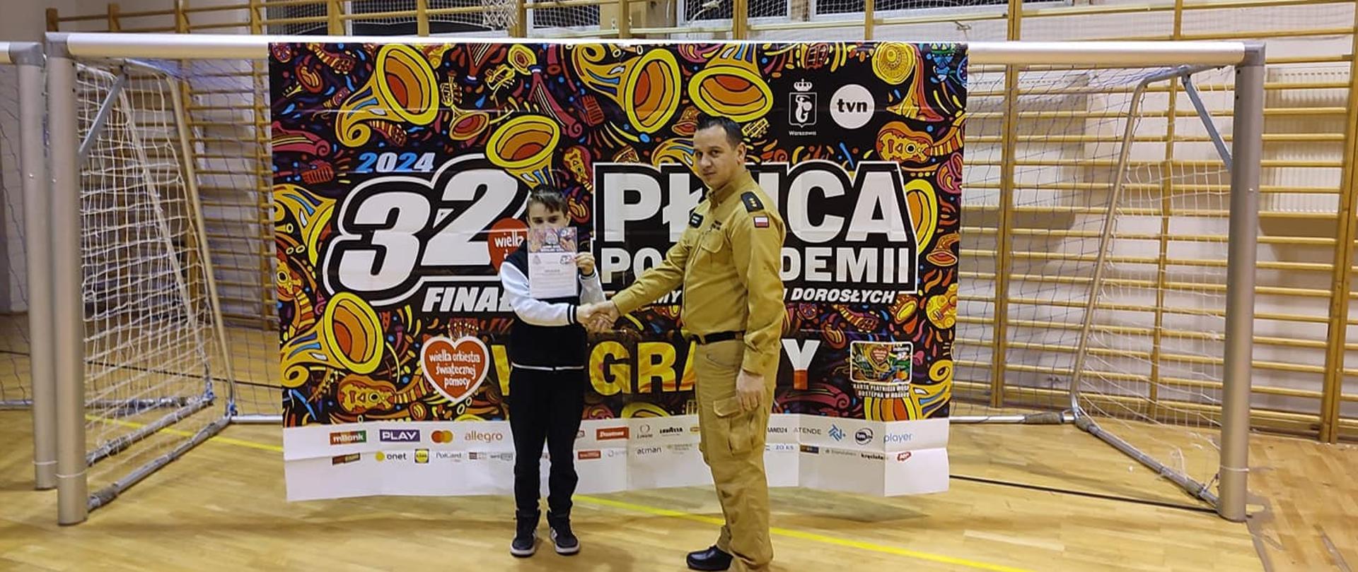 p. o. Komendanta Powiatowego kpt. Marcin Zięcina wręcza zwycięzcy licytacji voucher