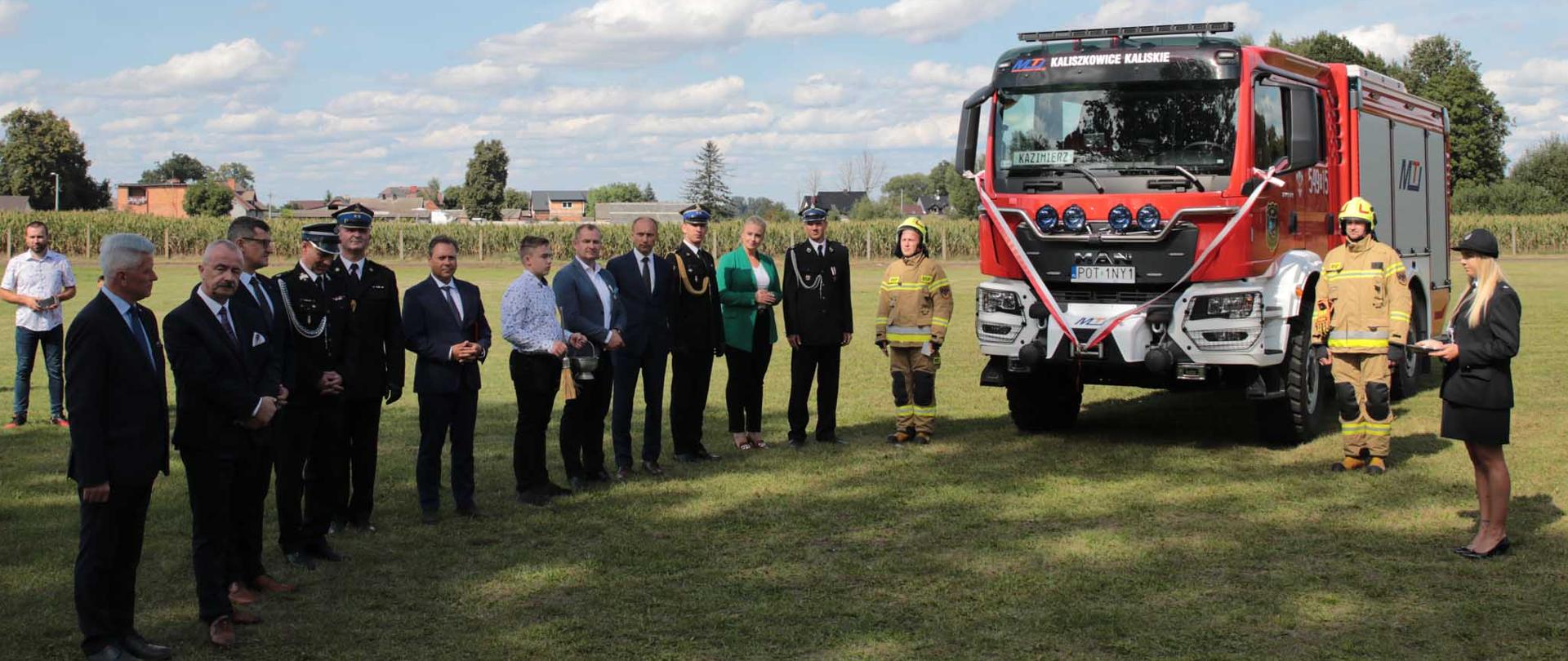 Uczestnicy uroczystości stoją przy nowym pojeździe