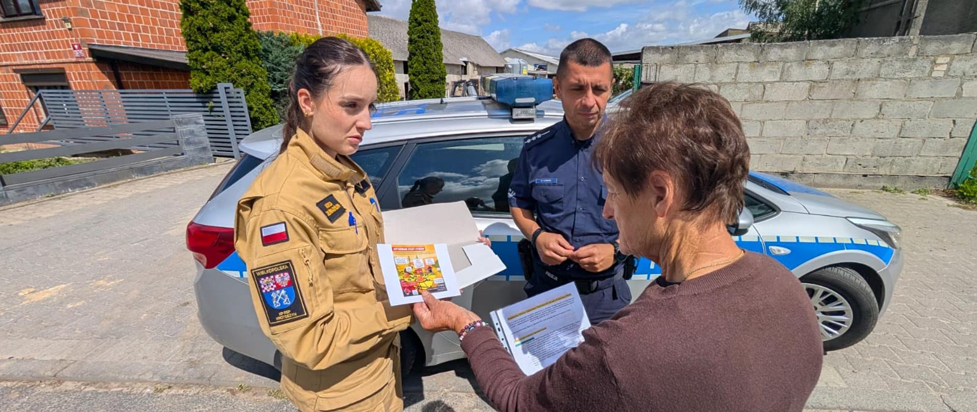 Zdjęcie przedstawia funkcjonariuszy straży pożarnej i policji podczas akcji edukacyjnej.