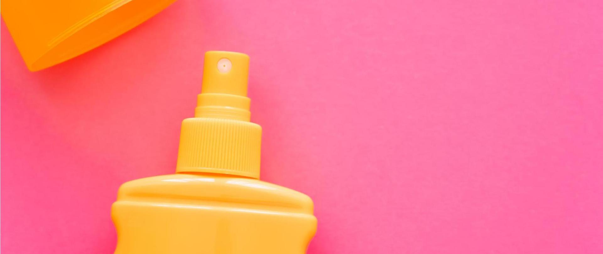 Na zdjęciu jest widoczna pomarańczowa butelka na różowym tle.