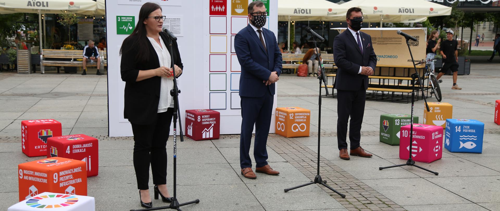 Na zdjęciu stoją od lewej: minister Małgorzata Jarosińska-Jedynak, wiceminister Grzegorz Puda, prezydent Katowic Marcin Krupa.W tle elementy przestrzenne promujące WUF, ONZ i Katowice.