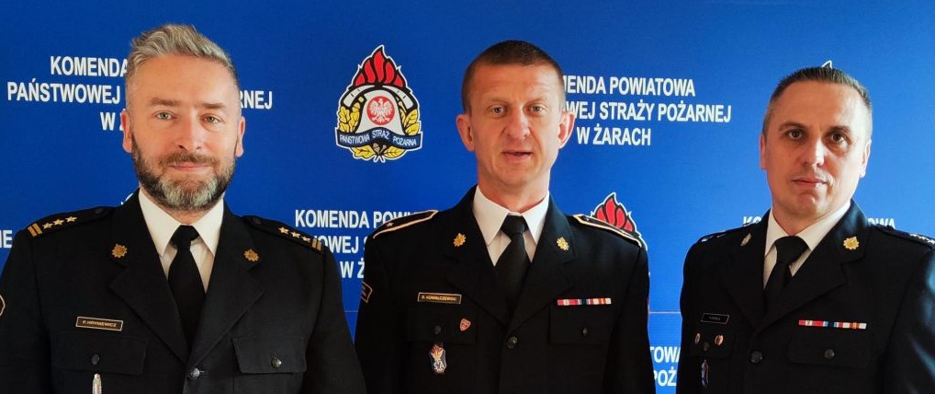 strażak otrzymał nagrodę w towarzystwie komendanta i dowódcy