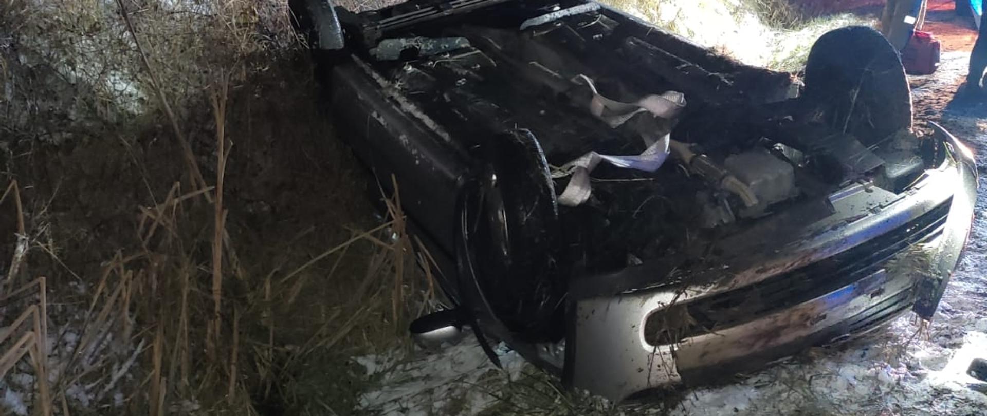 Zdjęcie przedstawia samochód osobowy znajdujący się na dachu.