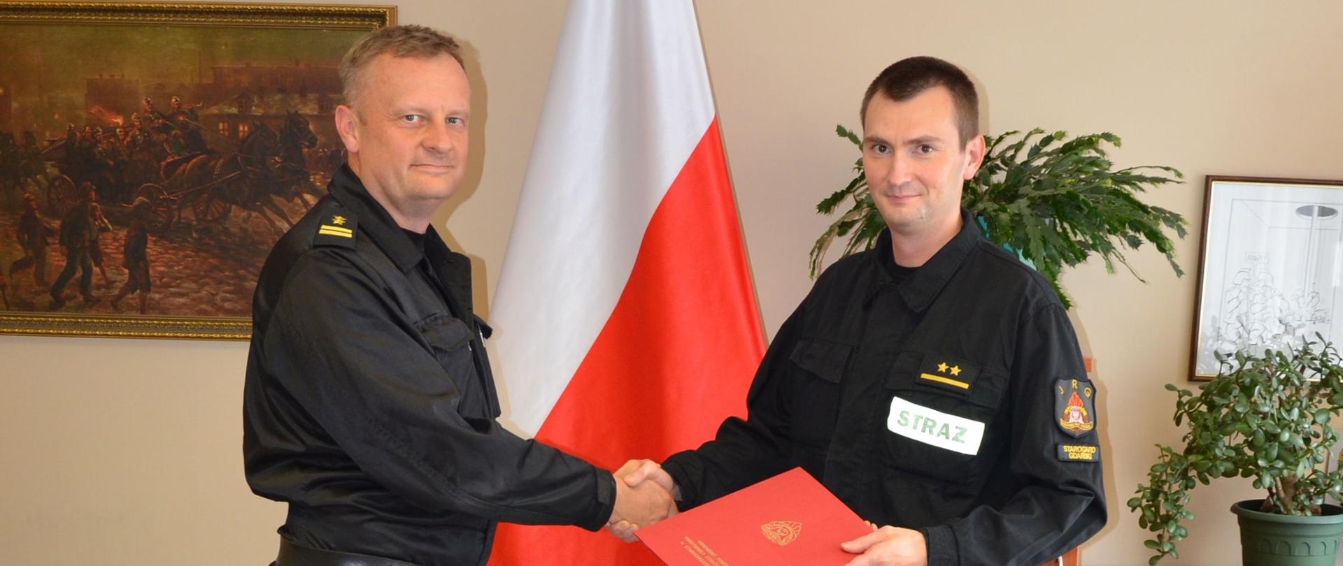 zdjęcie przedstawia Komendanta Powiatowego wręczającego nagrodę dla wyróżnionego funkcjonariusza