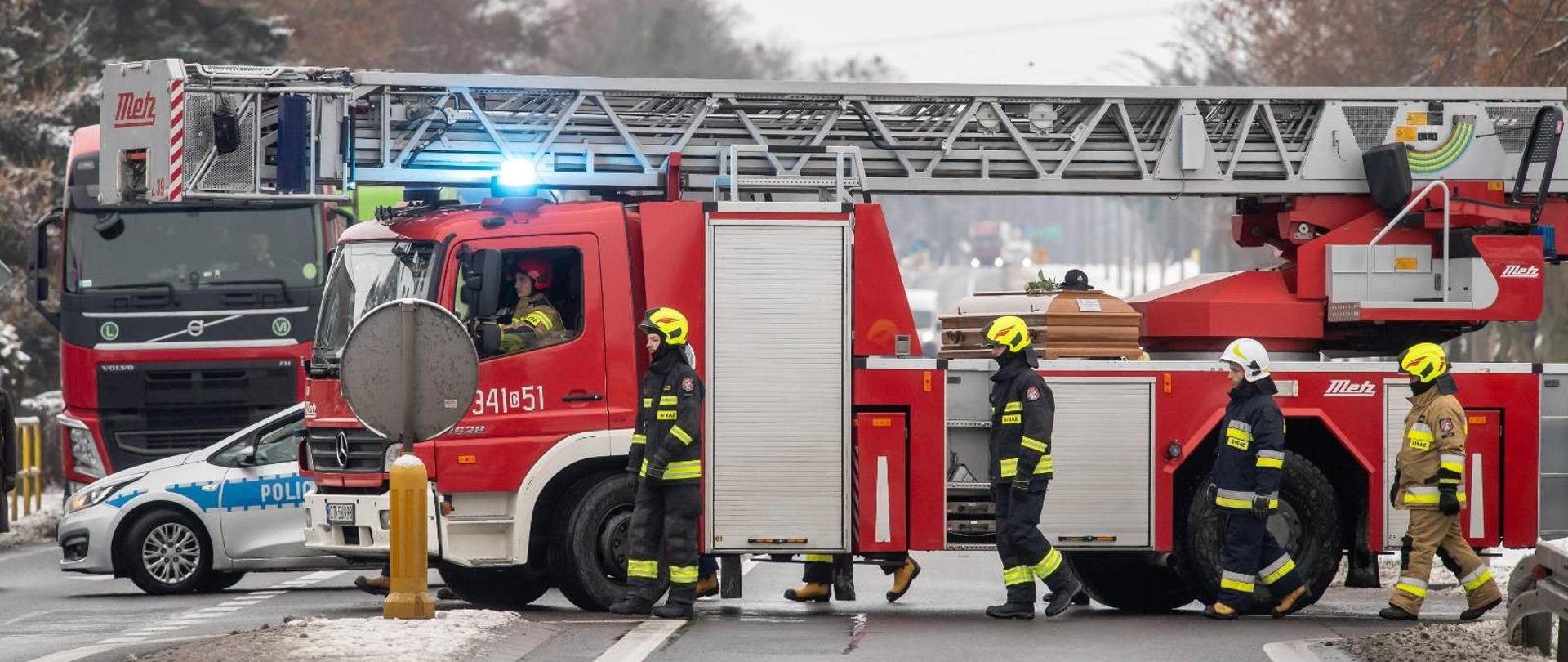 wóz strażacki, na nim trumna, obok strażacy w uniformach