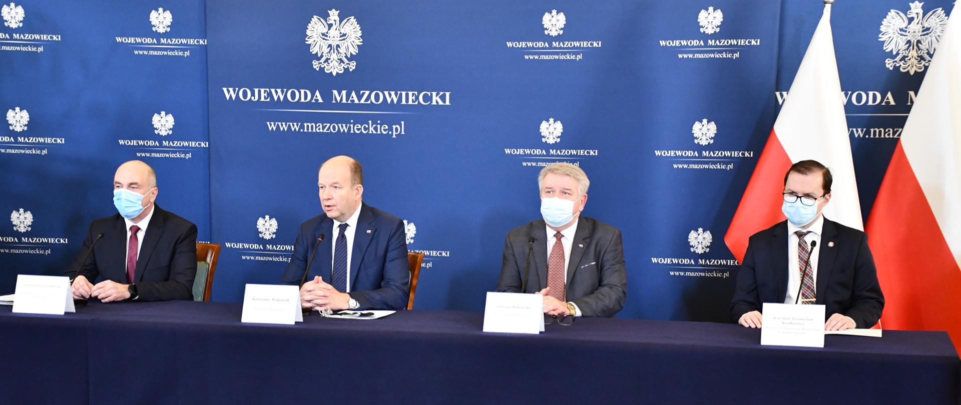 Na zdjęciu znajduje się czterech mężczyzn siedzących za stołem