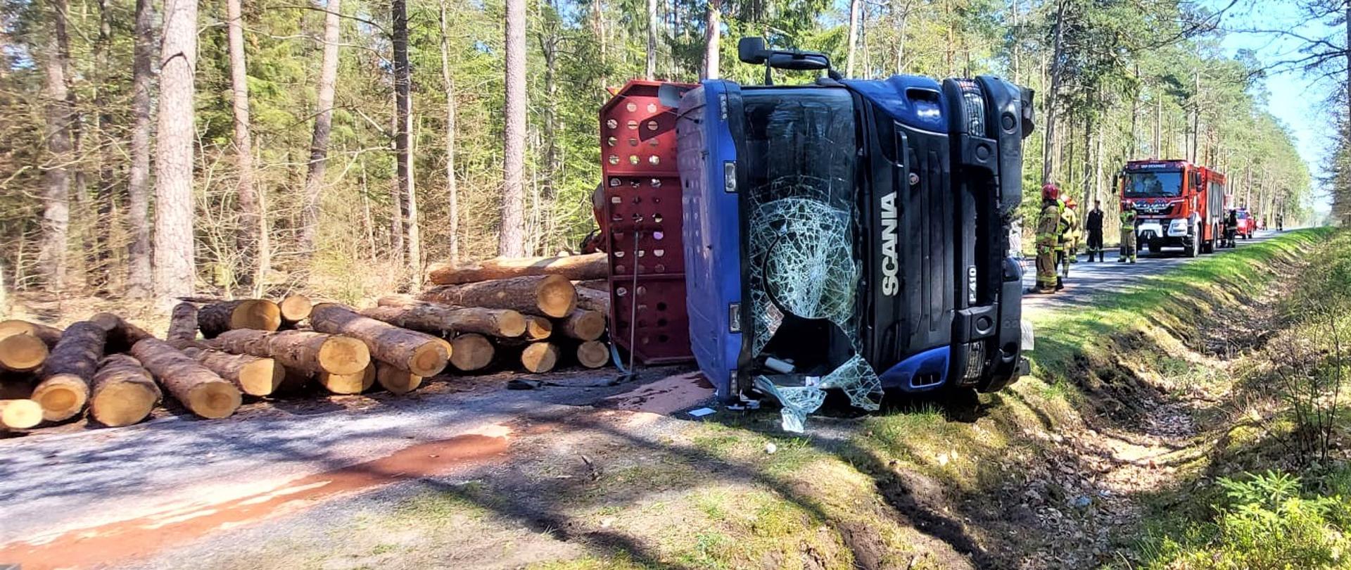 Zdjęcie pokazuje wywróciła się ciężarówka przewożąca drewno