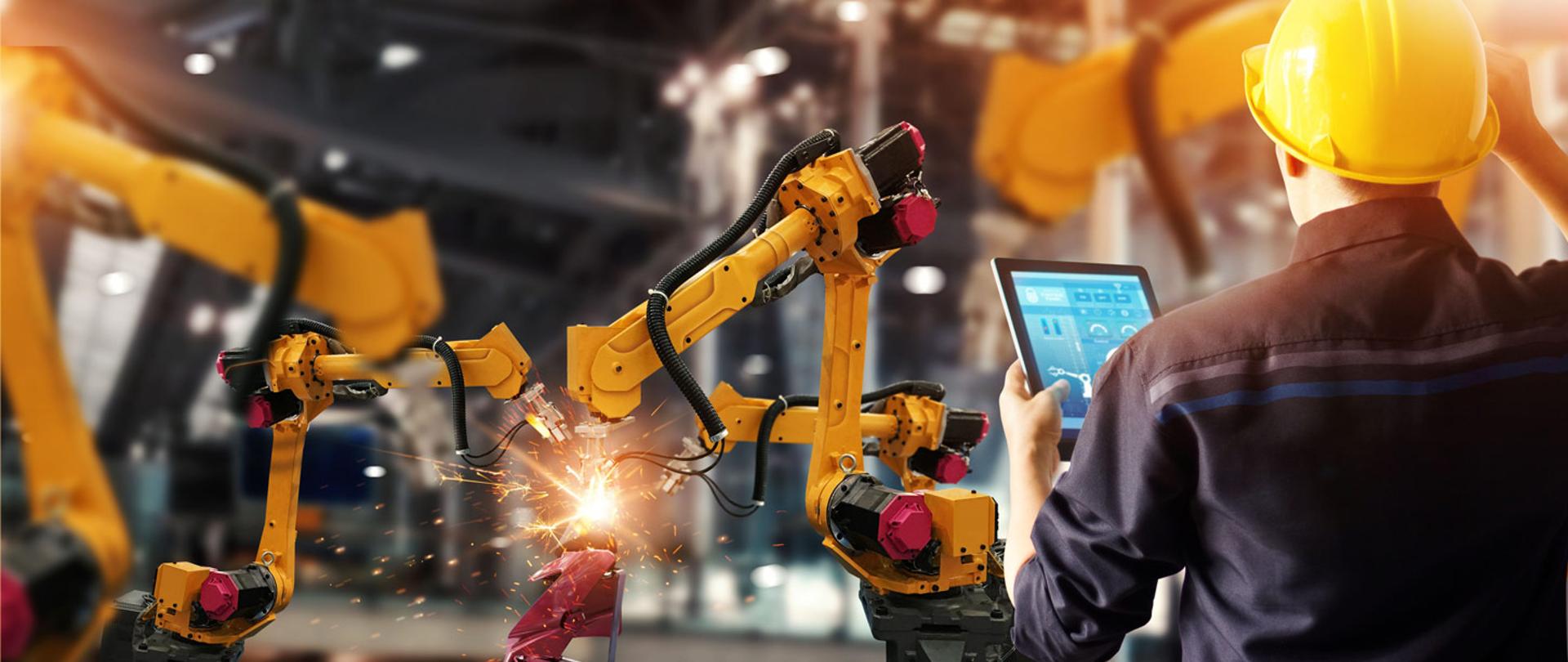 Inżynier sprawdza pracę automatycznego robota w nowoczesnej fabryce samochodów. 