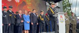 Małopolski KW PSP przemawia na trybunie honorowej. Za nim stoją zaproszeni goście