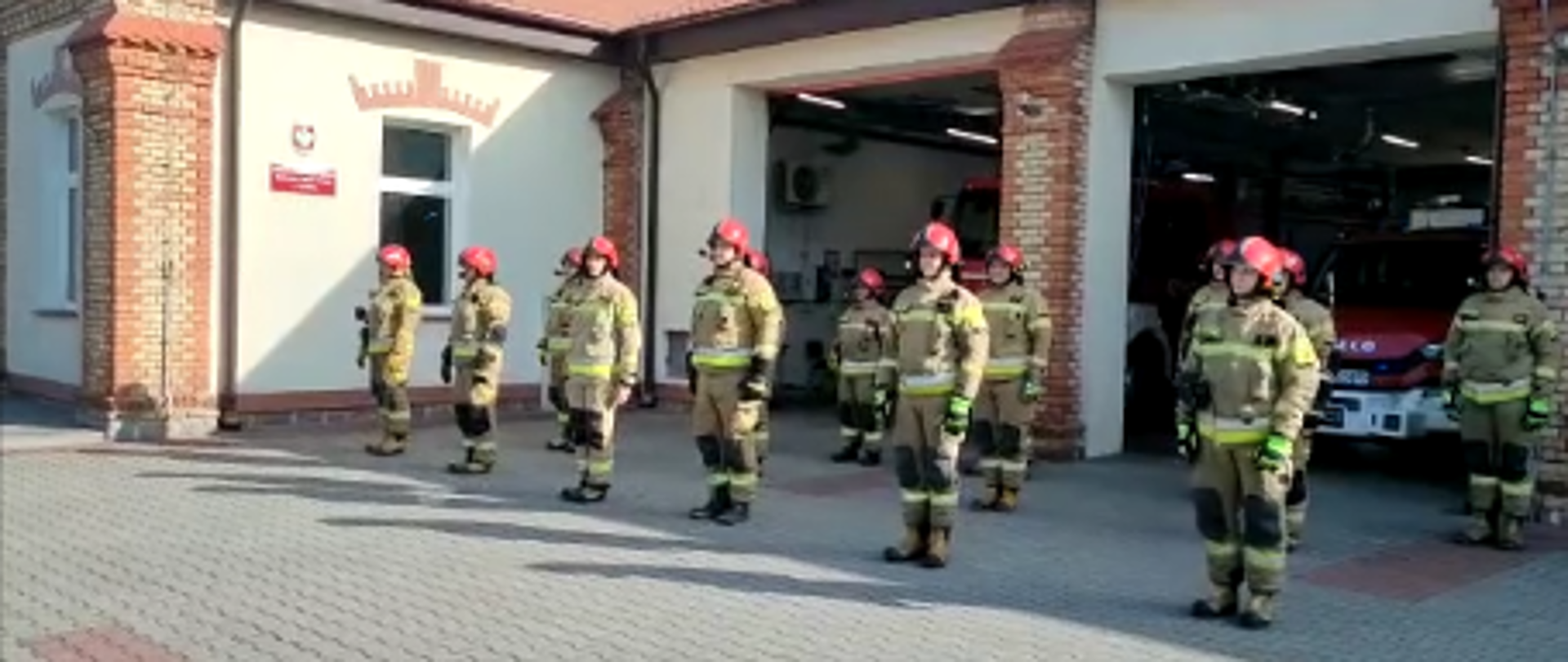 Strażacy PSP stoją przed budynkiem komendy