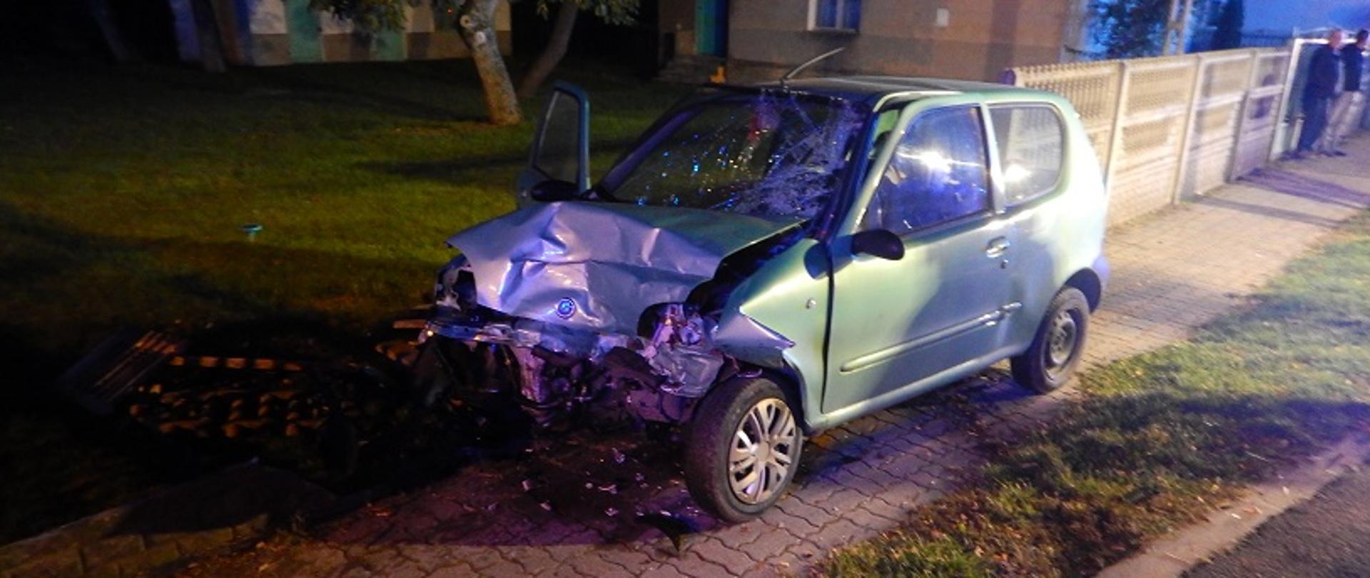 Zdjęcie przedstawia uszkodzony z przodu samochód osobowy marki Seicento po zderzeniu z samochodem osobowym marki Audi A6.