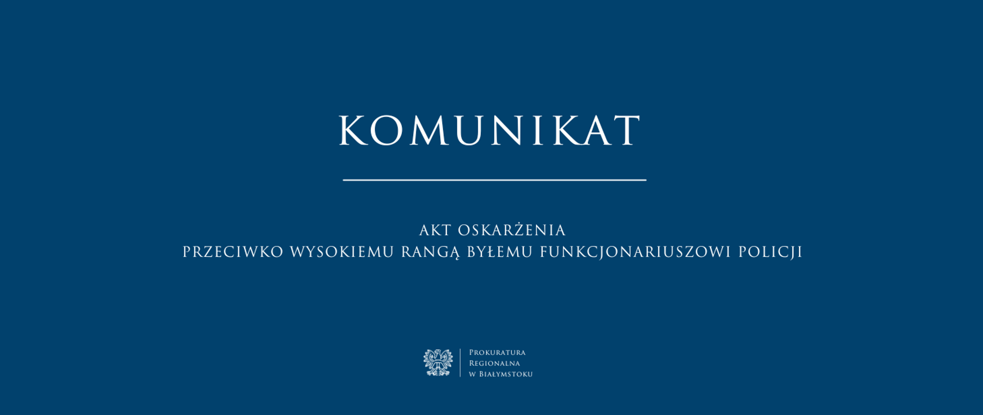 niebieskie tło na środku biały napis „komunikat” z białym podkreśleniem pod spodem tytuł „akt oskarżenia przeciwko wysokiemu rangą byłemu funkcjonariuszowi policji” oraz białe godło z nazwą jednostki Prokuratura Regionalna w Białymstoku