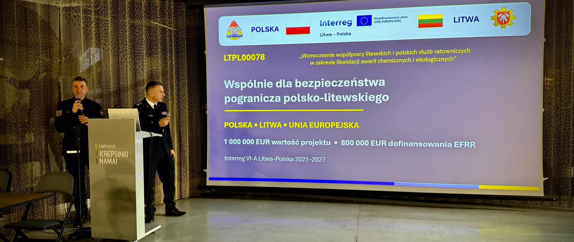 Współpraca ponad granicami, rezultaty na lata – zakończenie projektu LTPL00078 - Na zdjęciu st. bryg. Janusz Kondrat w tle prezentacja opisująca i promująca projekt Interreg