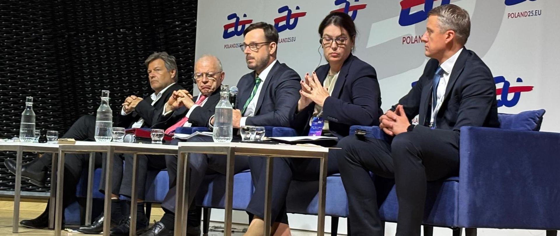 Minister Jakub Jaworowski wraz z innymi panelistami. W tle ścianka z logotypem polskiej prezydencji w Radzie UE.