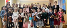 Grupa dzieci pozująca do zdjęcia grupowego wraz z nauczycielami podczas koncertu duetów skrzypcowych i nie tylko 23 lutego 2024 r.