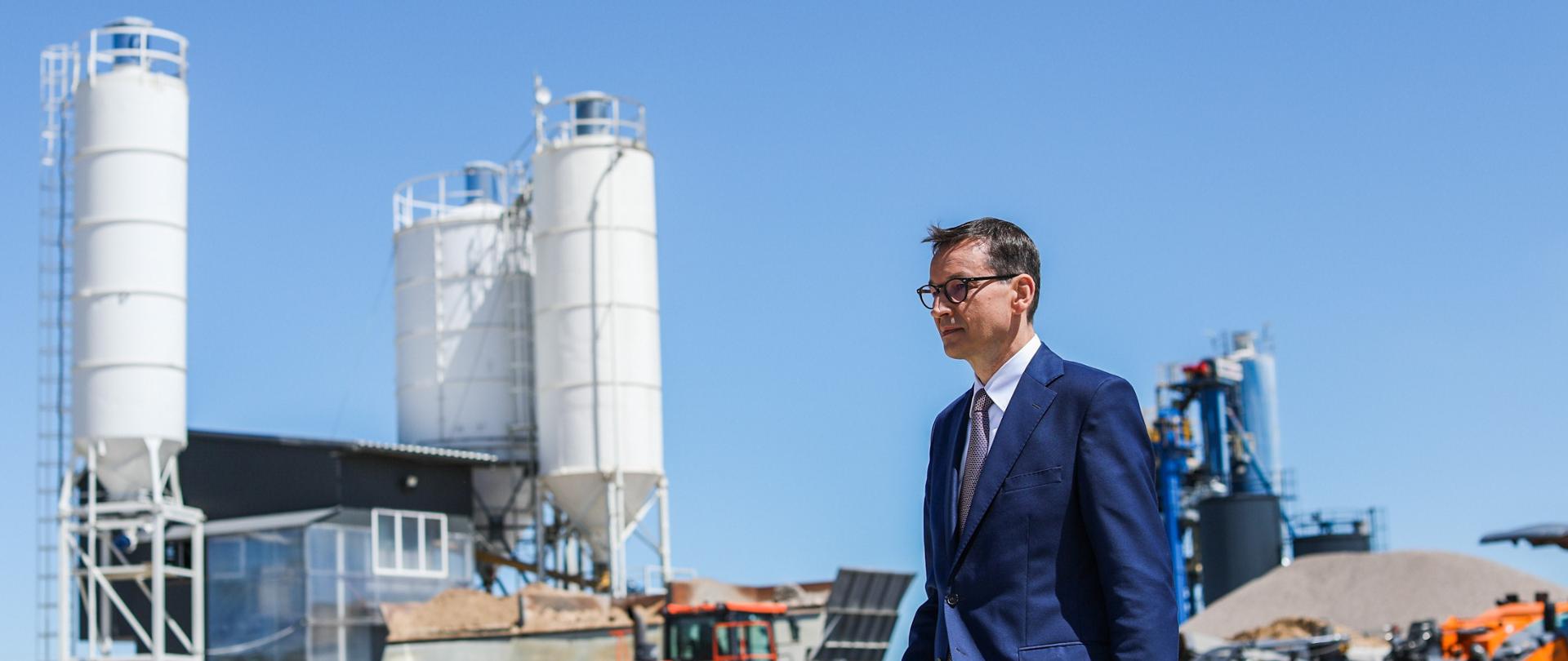 Premier Mateusz Morawiecki idzie, w tle maszyny.