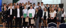 Zdjęcie grupowe. Na scenie stoją uczniowie klasy maturalnej i nauczycieli. 