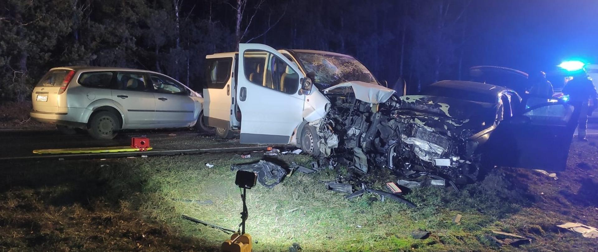 Trzy rozbite samochody stojące na jezdni po zderzeniu. W busie i jednym z samochodów osobowych całkowicie zniszczone przody.