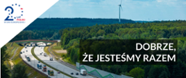 Droga wraz z przejściem dla zwierząt po trzy pasy w każdym kierunku. po prawej stronie las, po lewej ścieżka. Po drodze jadą głównie pojazdy ciężarowe. W lewym górnym rogu napis 20 lat Polski w Unii Europejskiej.