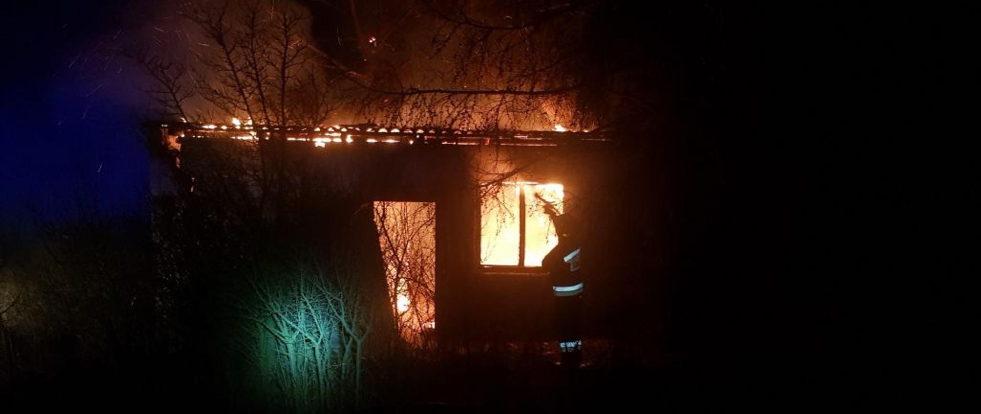 Strażak gasi płonący pustostan