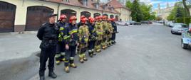2 Na zdjęciu widać strażaków z JRG 4 uczestniczących w uroczystym przekazaniu sprzętu. Strażacy ubrani w ubrania specjalne i hełmy strażackie.