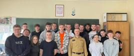 Na zdjęciu znajdują się uczniowie i strażak ustawieni w klasie