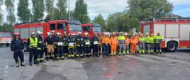 zdjęcie przedstawia kilkudziesięciu strażaków i pracowników cementowni pozujących do pamiątkowego zdjęcia po przeprowadzonych ćwiczeniach na terenie cementowni Lafarge Cement 