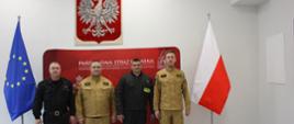 Na zdjęciu komendanci dowódca jednostki oraz nagrodzony strażak w tle baner straży pożarnej