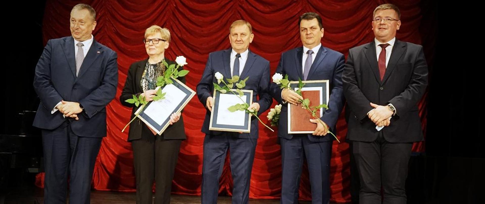 Wiceminister Tomasz Rzymkowski na obchodach Dnia Edukacji Narodowej w Kutnie, wiceminister Tomasz Rzymkowski stoi na scenie w towarzystwie nagrodzonych nauczycieli.