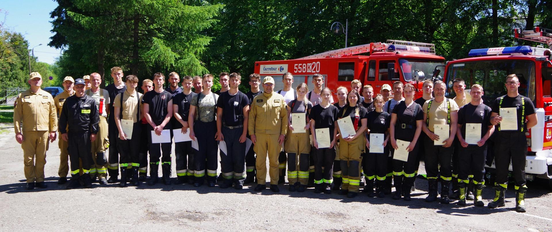 Zdjęcie grupowe – uczestnicy szkolenia OSP i kadra KP PSP Wadowice na tle samochodów pożarniczych.