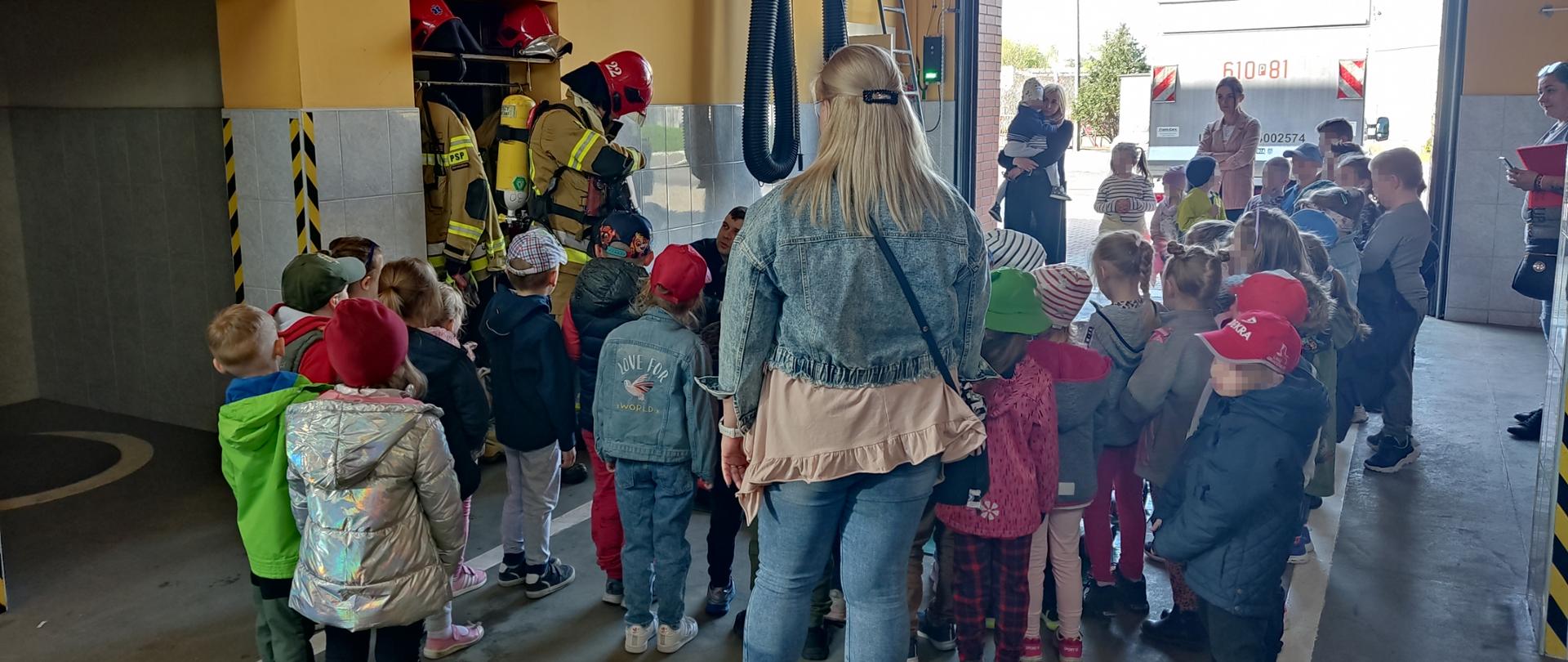 Dzieci z przedszkola wraz z wychowawcami oglądają w garażu Komendy pokaz strażackiego sprzętu i umundurowania 