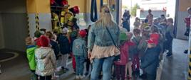 Dzieci z przedszkola wraz z wychowawcami oglądają w garażu Komendy pokaz strażackiego sprzętu i umundurowania 