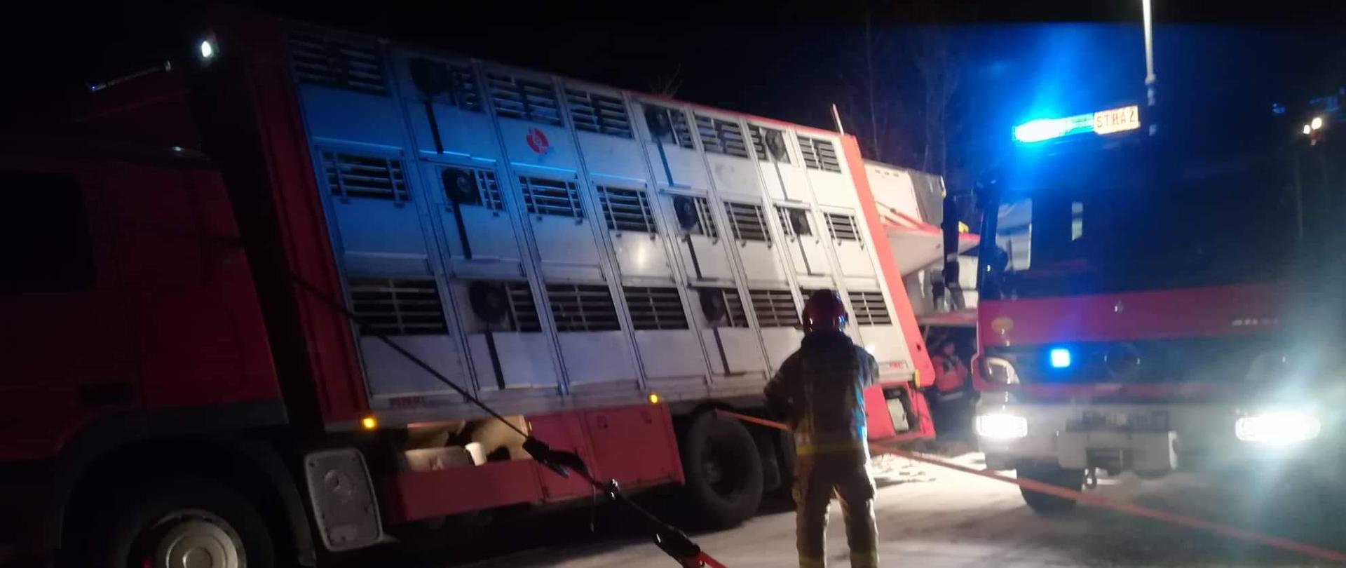 Samochód ciężarowy z oblodzonej drogi ześlizgnął się do rowu. Przechylił się i został przymocowany pasami żeby się nie przewrócił.