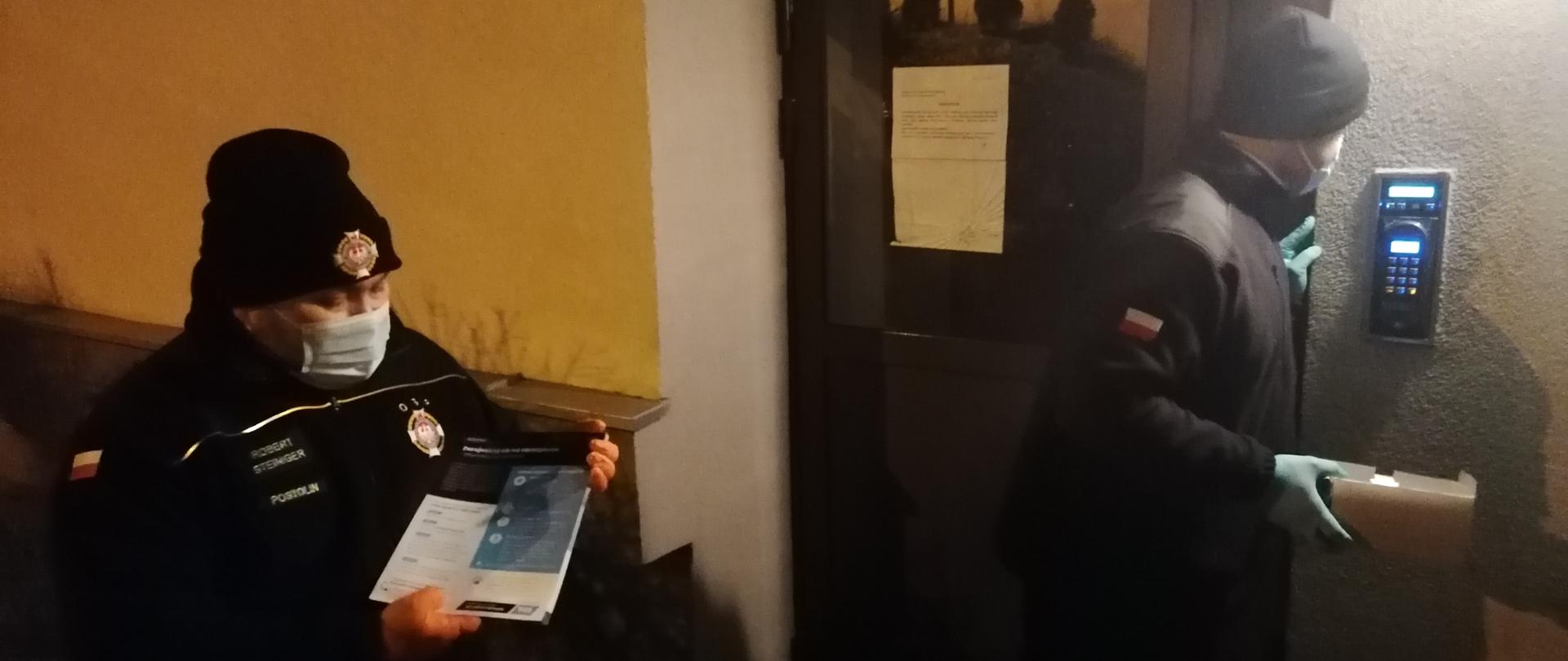 dwóch druhów OSP z ulotkami w ręku starają się skomunikować przez domofon z mieszkańcami.