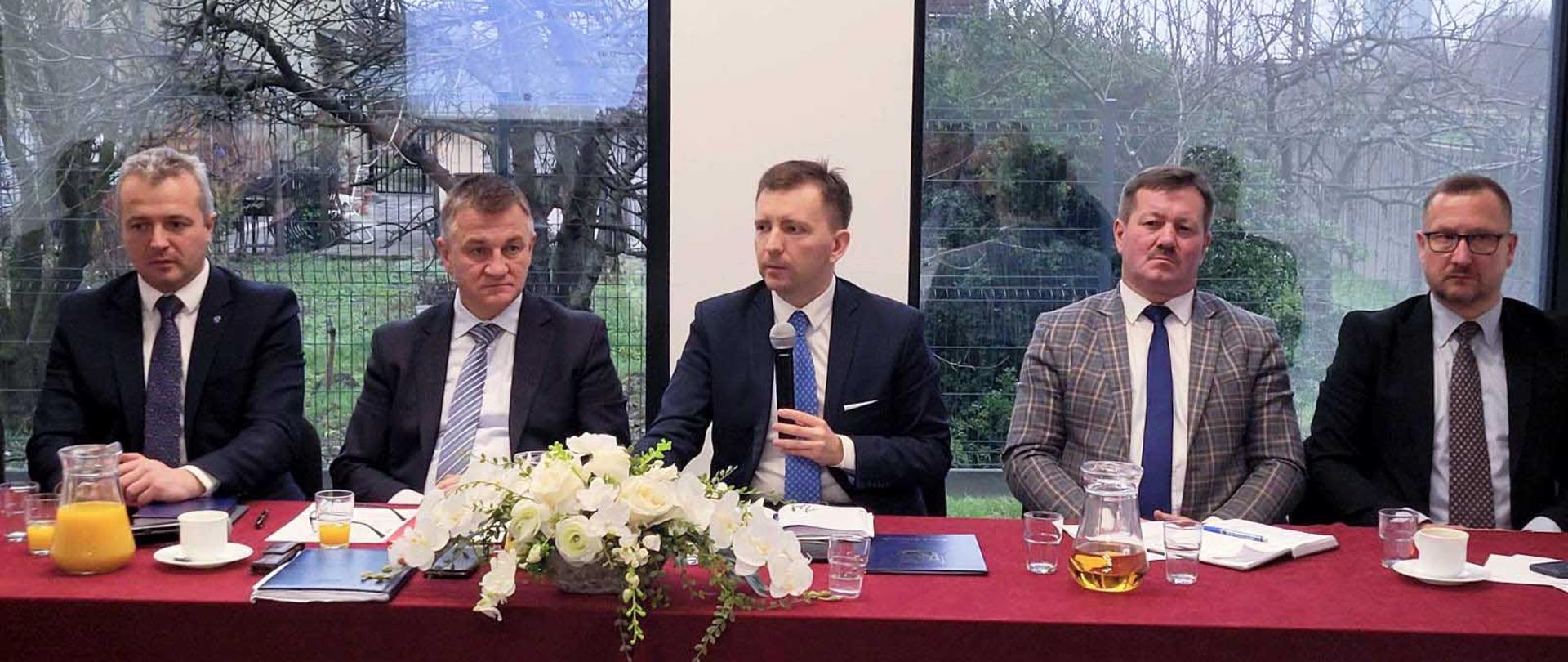 Pięciu mężczyzn siedzących przy stole 